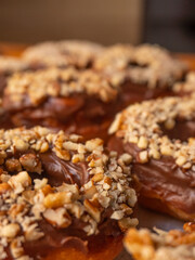 Chocolate donuts with pieces of nuts and background with more donuts