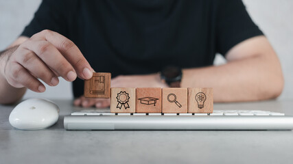 Course education or e-learning concept. Computer study technology, book, bow, graduate cap, search and idea. Man holding icon on wood block row with icons of education on keyboard. Teaching concept - Powered by Adobe