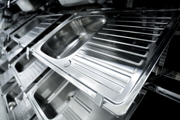 Angle view of rows metal kitchen sink at the showroom of a large store. 