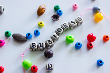 Word business made from colored beads on the thread, concept of designing or occupation of hand made, light background