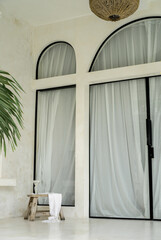 Modern luxury villa with large black framed arched windows and doors. Details of modern style design interior in modern, minimal, white Villa in Bali. Bohemian (Boho) and Scandinavian rustic home  © Ruth