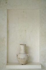 Rustic, large white, oversized ceramic vase on a shelf in modern, minimal, white Villa in Bali. Bohemian (Boho) and Scandinavian rustic home interior, white villa, modern luxury villa. Modern exterior
