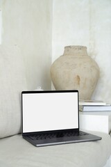 Laptop MacBook Pro computer mockup with white screen on white cushioned indoor outdoor style sofa...