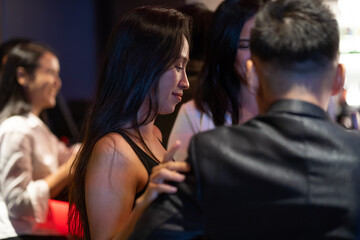 Fototapeta premium Diverse group of friends partying in nightclub and toasting drinks. Asian female drink intoxicating drink