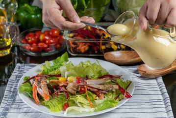 woman chef mix fresh baby cos salad and pour salad dressing in glass blow. Organic Vegetables mix all green salad In glass bowl. Breakfast fresh salad and clean vegetable.