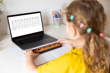 A girl from the back is engaged in mental arithmetic on the abacus online on a laptop, chroma key background. The concept of teaching children to count quickly, Russian mathematics. - obrazy, fototapety, plakaty