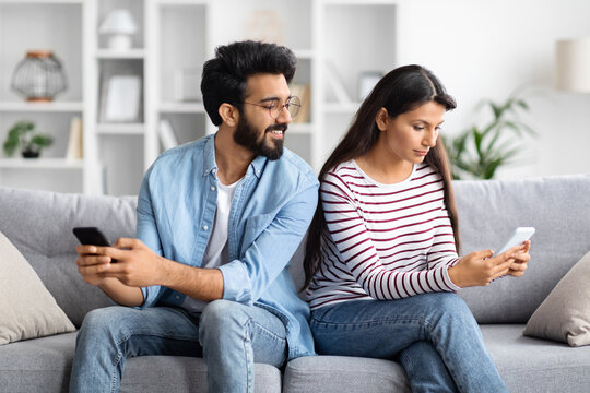 Young indian wife using mobile phone, husband watching spying Generative AI