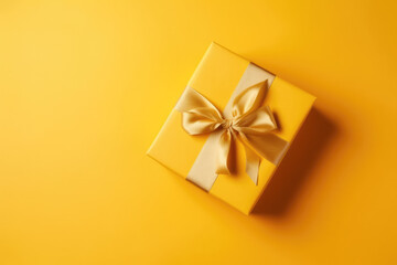 Obraz na płótnie Canvas Gift box with golden satin ribbon and bow on yellow background. 