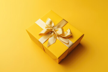 Obraz na płótnie Canvas Gift box with golden satin ribbon and bow on yellow background. 