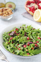 A plate with green rocket salad with pomegranate