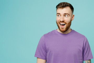 Young impressed surprised shocked european cool fun man he wearing purple t-shirt look aside on workspace area isolated on plain pastel light blue cyan background studio portrait. Lifestyle concept.