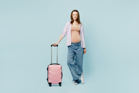Full body young pregnant mom woman with belly tummy with baby wear casual clothes hold bag isolated on plain blue background. Tourist travel abroad in free time rest getaway. Air flight trip concept.