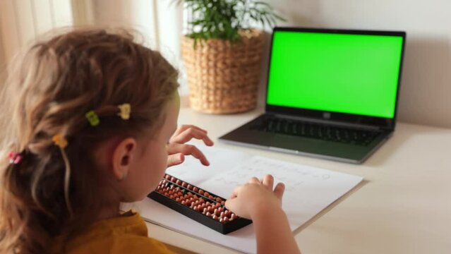 A girl from the back is engaged in mental arithmetic on the abacus online on a laptop, chroma key background. The concept of teaching children to count quickly, Russian mathematics.