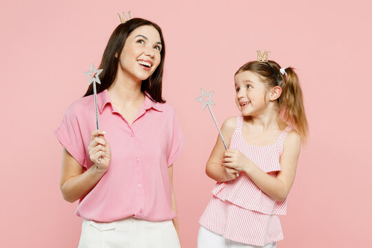 Happy woman wear casual clothes diadem princess crown with child kid girl 6-7 years old. Mother daughter hold magic wand fairy stick isolated on plain pastel pink background Family parent day concept