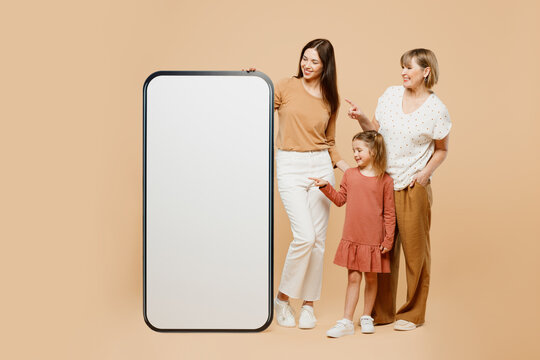 Full body women wear casual clothes with child kid girl 6-7 years old. Granny mother daughter near big huge screen area mobile cell phone isolated on plain beige background. Family parent day concept.