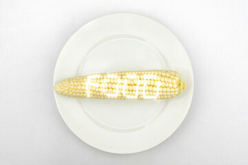 Corn with glowing food text on a white plate.