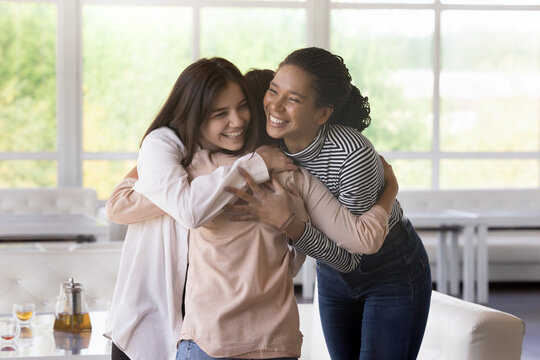 Multi ethnic girls, best friends greet, meet each other in lounge cafe, hugging with love and affection, express warmth, enjoy their strong friendship gathered in public place. Generative AI