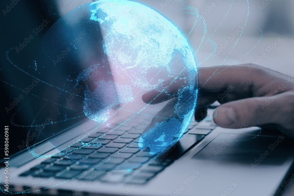 Poster close up of businessman hand using laptop keyboard at desktop with glowing blue polygonal globe on b