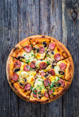 Circle pizza with sausages, onion and mozzarella cheese on wooden table 