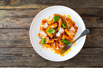 Noodles with pesto, parmesan cheese and basil leaves served on wooden table
