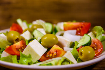 Ceramic plate with greek salad on wooden table