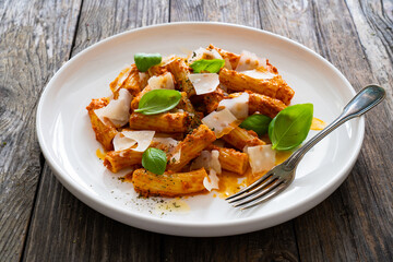Noodles with pesto, parmesan cheese and basil leaves served on wooden table
