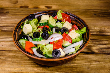 Ceramic plate with greek salad on wooden table