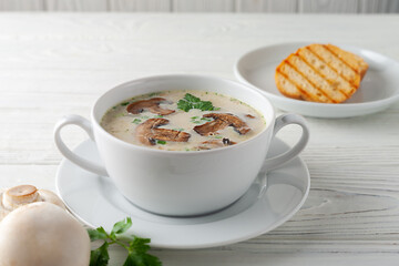 Mushroom cream soup on a white wooden board. side view