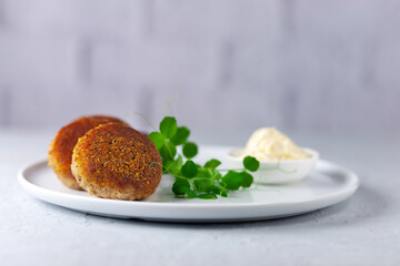 Fish cutlets with mayonnaise on a white plate.