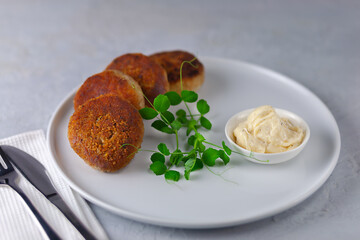 Fish cutlets with mayonnaise on a white plate.