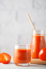 Glass of tomato juice with vegetables on white brick wall background