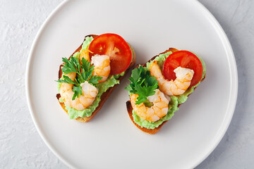 Healthy snack or shrimp bruschetta with avocado and bread. Fried shrimp and mashed avocado on toasted bread