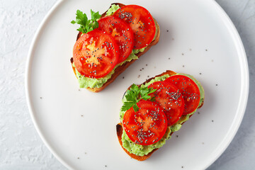 Vegan sandwich with avocado and tomatoes on a white dish
