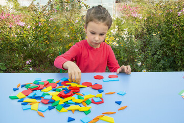 A girl plays with the figures of a constructor on the street