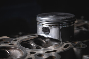 a new repair piston of the internal combustion engine lies on a disassembled engine in the workshop