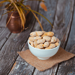 peanut  in a white bowl on wooden table  