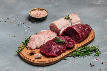 raw pork meat and beef with rosemary and spices on a wooden board. Restaurant menu, dieting, cookbook recipe. place for text