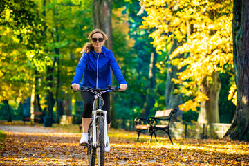 Urban biking - woman riding bike in city park
