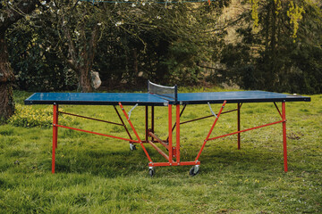 Ping pong table on green grass. Folding table for playing small tennis. Active leisure.