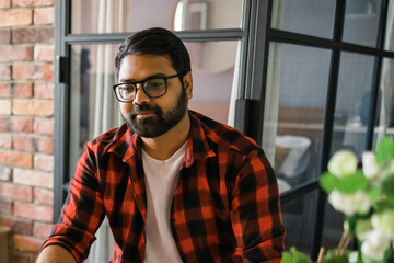 Head shot portrait smart confident smiling millennial indian man. Handsome hindu student guy freelancer at home