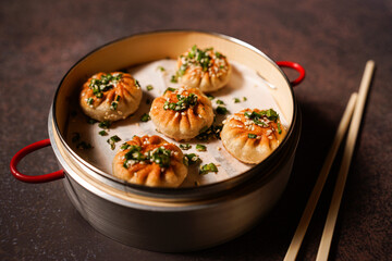 Traditional dumplings in bamboo steamer with sauces and chopsticks on dark, wooden surface with copy space, food background, dumpling steamer basket, gyoza, dimsum,  menu, oriental, fine dining
