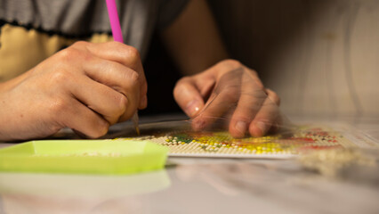 The girl collects a diamond mosaic close-up, top view