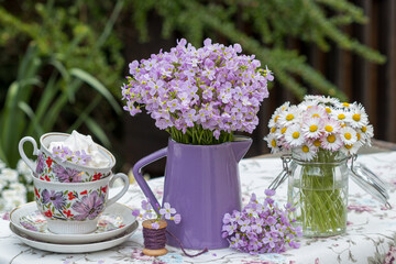 Arrangement mit Blumenstrauß mit Wiesen-Schaumkraut und Gänseblümchen und vintage Porzellan-Tassen 