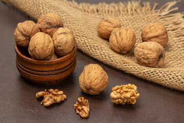 Walnuts in wooden bowl. Walnut kernels on the table. Whole nuts on burlap napkin.
