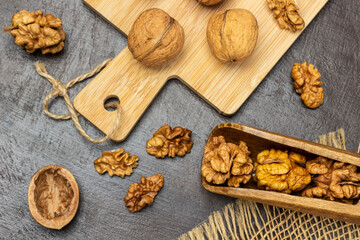 Walnut kernels in wooden scoop and on table. Whole nuts on board.