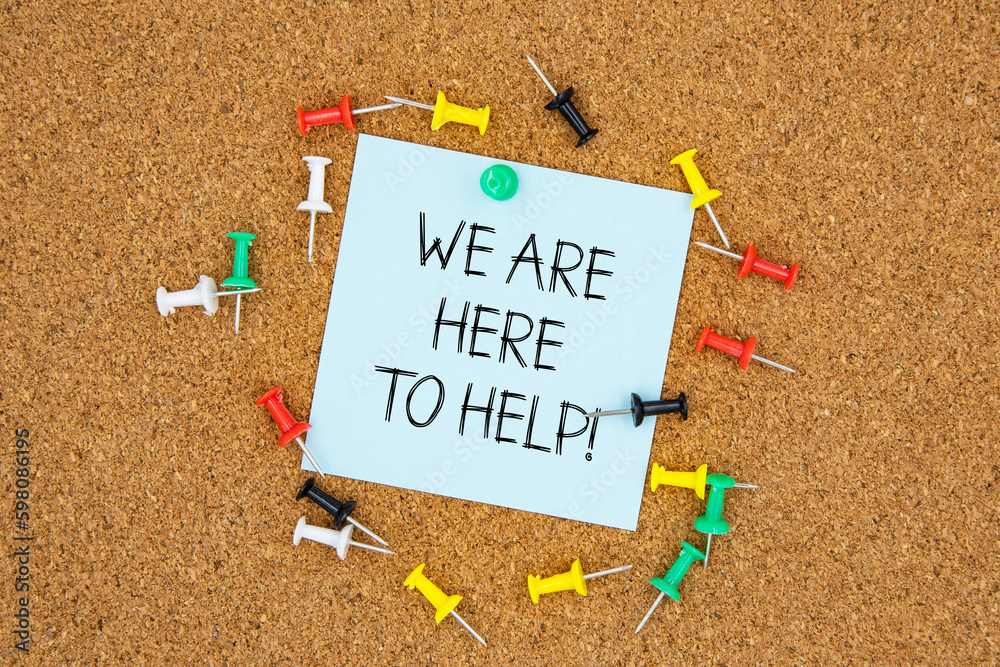 Fototapete we are here to help text on light blue post-it paper pinned on bulletin cork board surrounding by mu