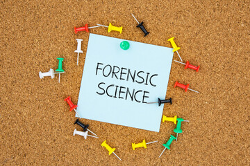 Fornsic science text on light blue post-it paper pinned on bulletin cork board surrounding by multi color pins. This message can be used in business concept about forensic science.