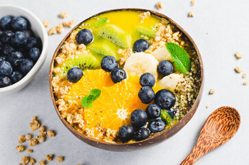 Smoothie Bowl with Orange, Kiwi, Banana, Blueberry, and Granola in a Coconut Bowl, Healthy Food Concept