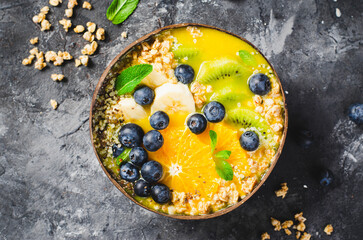 Smoothie Bowl with Orange, Kiwi, Banana, Blueberry, and Granola in a Coconut Bowl, Healthy Food Concept