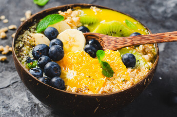 Smoothie Bowl with Orange, Kiwi, Banana, Blueberry, and Granola in a Coconut Bowl, Healthy Food Concept
